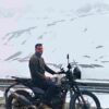 Group of bikers on the Delhi to Ladakh bike trip riding through Himalayan roads toward Leh with prayer flags and rugged landscapes