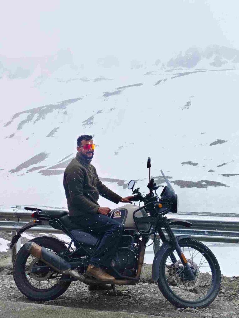 Group of bikers on the Delhi to Ladakh bike trip riding through Himalayan roads toward Leh with prayer flags and rugged landscapes