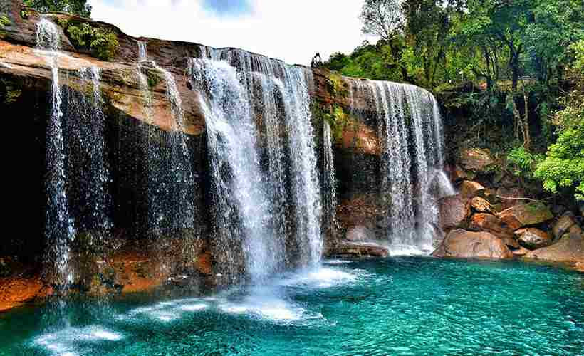 Tourists swimming in the clear blue waters of Krang Suri Falls