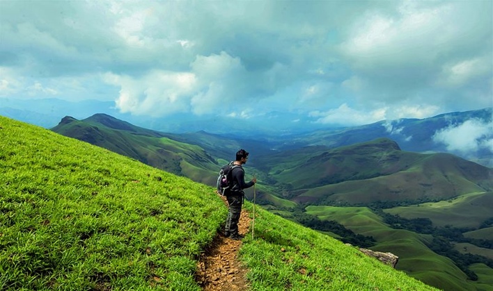 Rolling green hills of Kudremukh Trek with monsoon clouds above